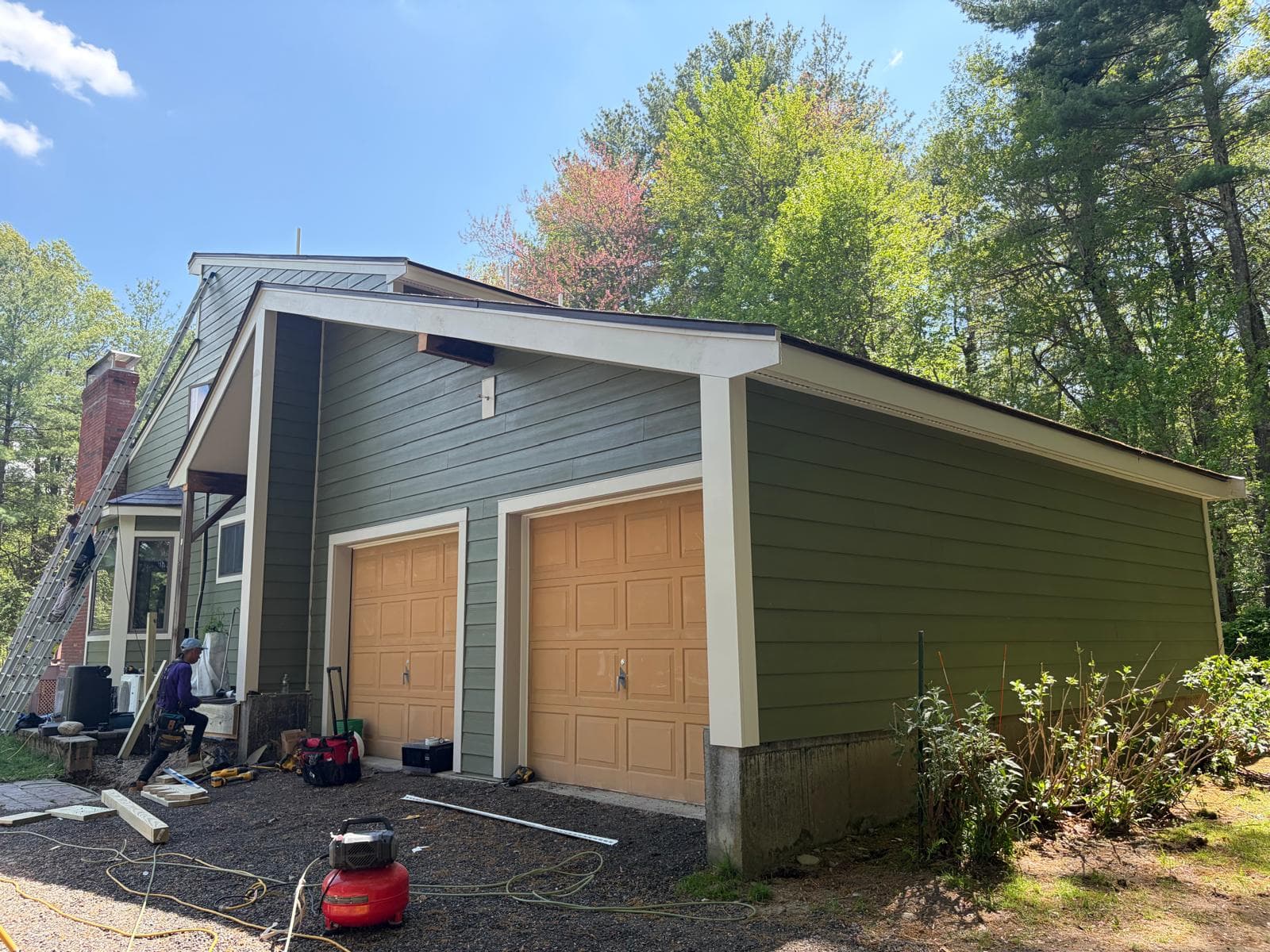 Completed Carlisle home garage side — James Hardie ColorPlus green siding with cream HardieTrim around orange garage doors
