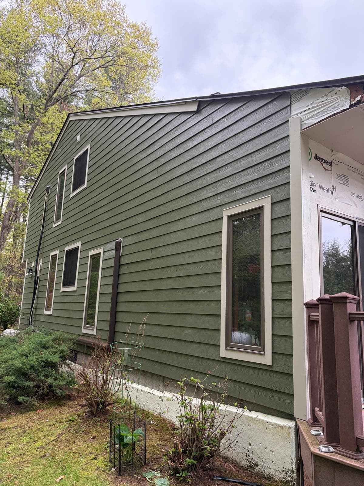 Close-up of finished James Hardie ColorPlus green siding on Carlisle MA home with cream window trim