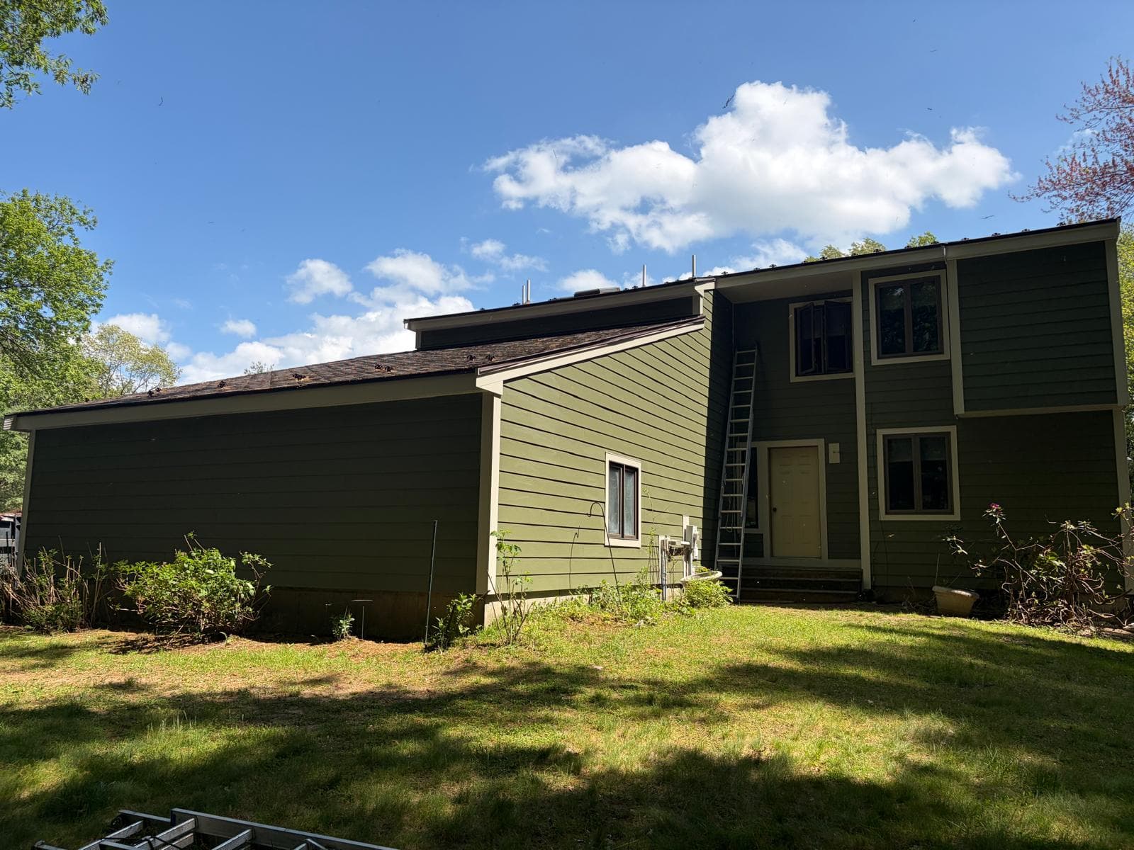 Side elevation of finished Carlisle MA home in James Hardie ColorPlus green plank with cream window trim