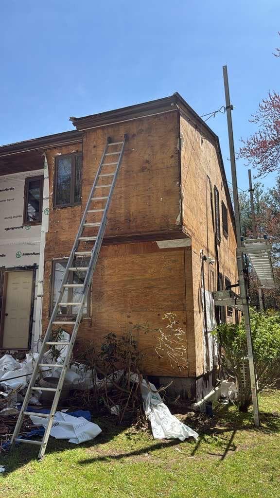 Carlisle home with plywood exposed and demo debris on the ground after old siding removal