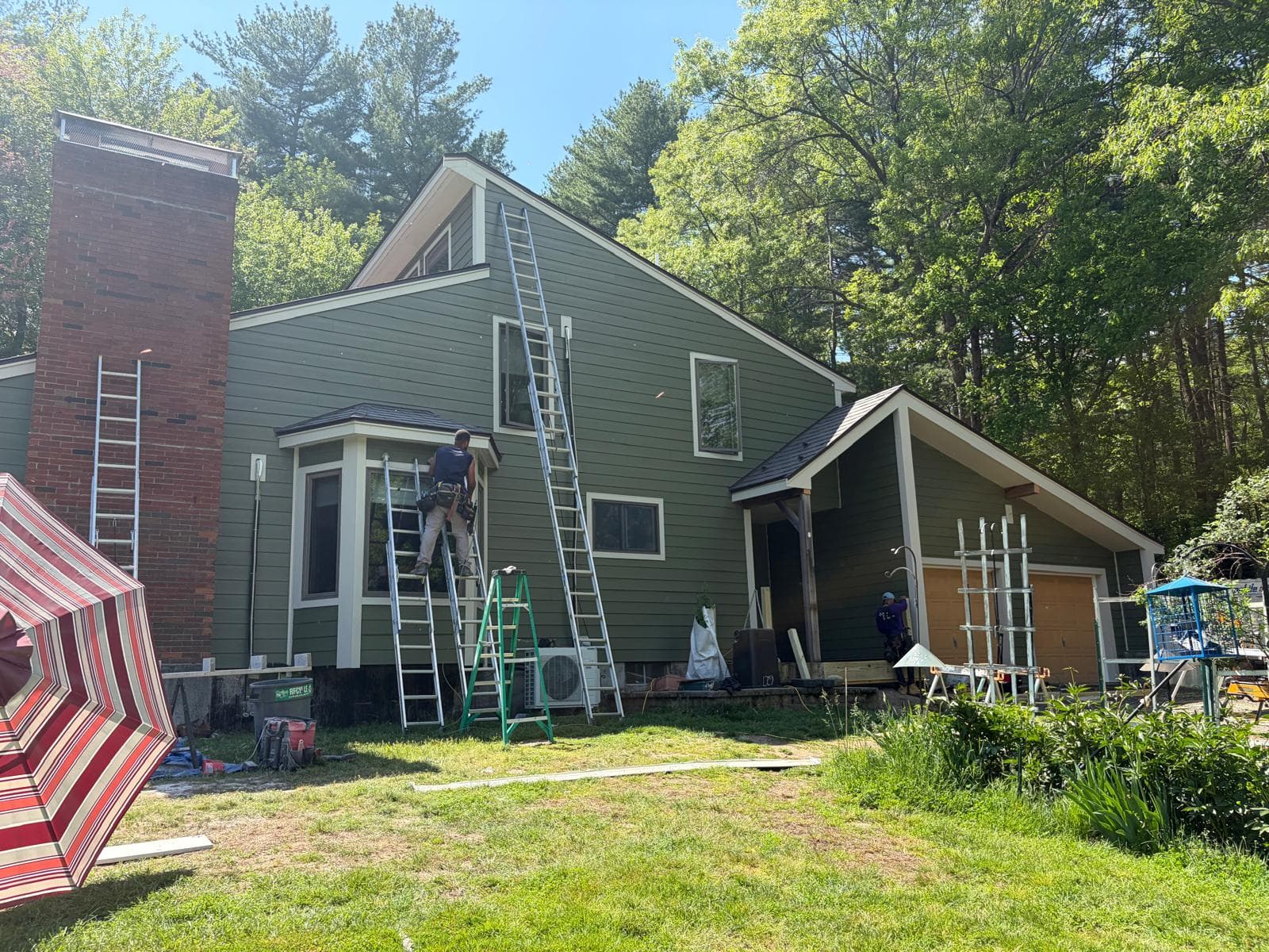 Carlisle MA home with James Hardie green plank siding completed — daytime front elevation with workers visible