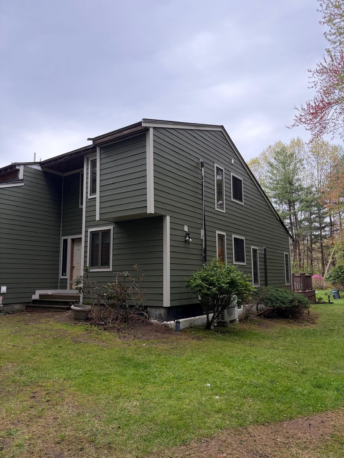 Carlisle MA home mid-install — lower walls in James Hardie ColorPlus green plank, upper still in HardieWrap