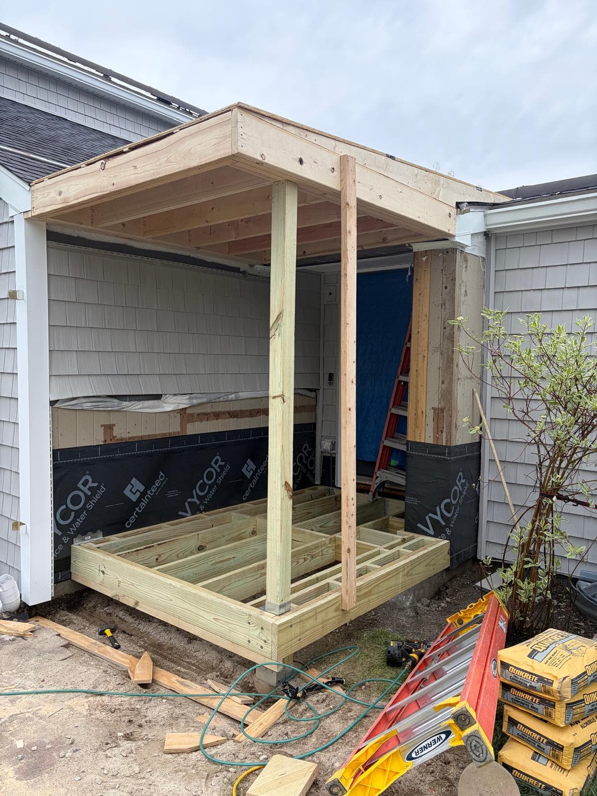 Webster MA porch addition framing with Vycor water shield, vertical posts, and tools on site